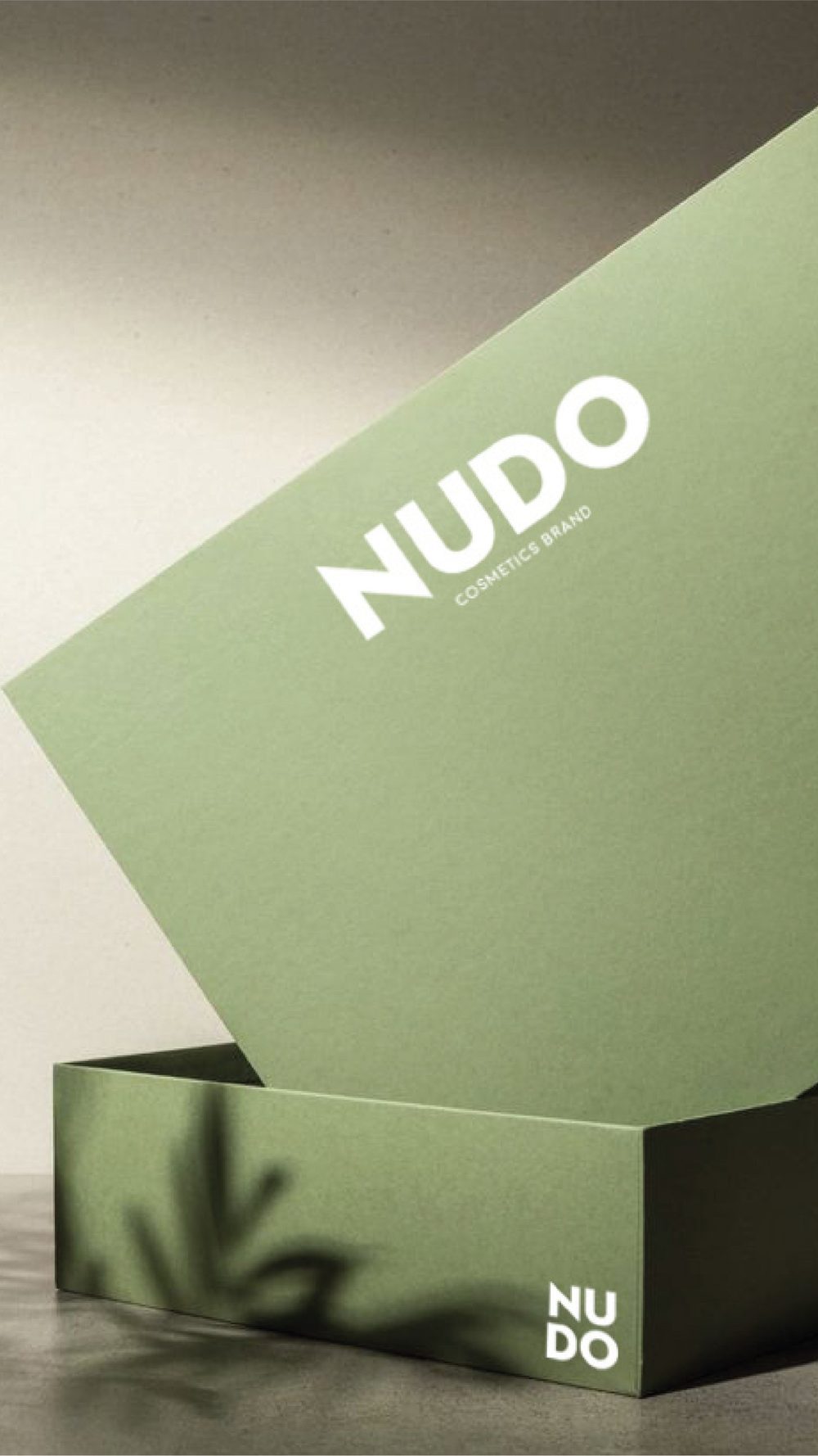 Scatola verde salvia aperta con il logo Nudo e l’ombra di una pianta